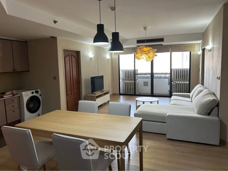Spacious modern living room with open layout, featuring a cozy sofa, dining area, and washing machine.