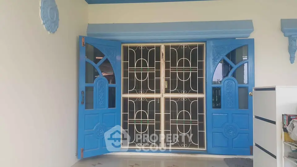 Charming blue entrance door with decorative metal grill in a stylish home exterior.