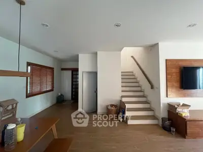Spacious modern living room with wooden accents and staircase, perfect for family gatherings.