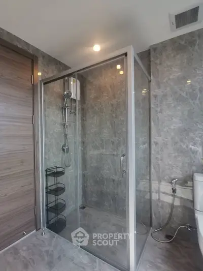 Modern bathroom with glass shower enclosure and marble walls