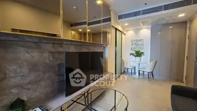 Modern living room with sleek TV setup and cozy dining area in a stylish apartment.