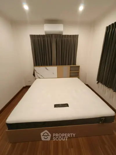 Cozy bedroom with modern design and air conditioning, featuring a comfortable bed and elegant curtains.
