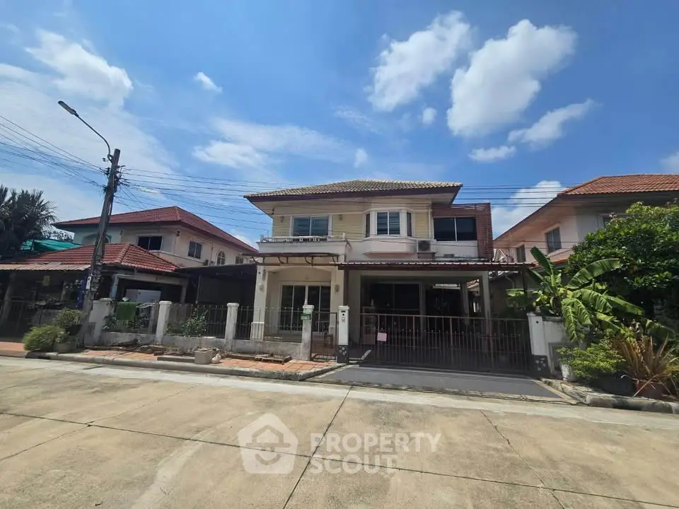 Charming two-story suburban house with spacious driveway and lush greenery under a clear blue sky.