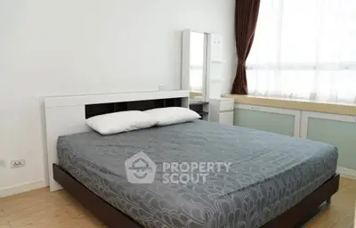 Spacious bedroom with modern furnishings and large window for natural light.