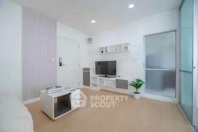 Modern living room with sleek design, featuring a wall-mounted TV, stylish furniture, and bright lighting.