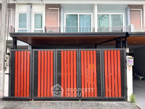 Modern townhouse exterior with striking red and black gate design.