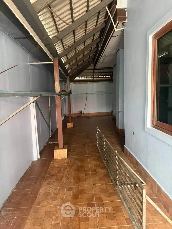 Spacious covered outdoor area with tiled flooring and wooden beams, ideal for versatile use.