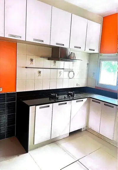 Modern kitchen with sleek cabinets and gas stove, vibrant orange accents, and natural light.
