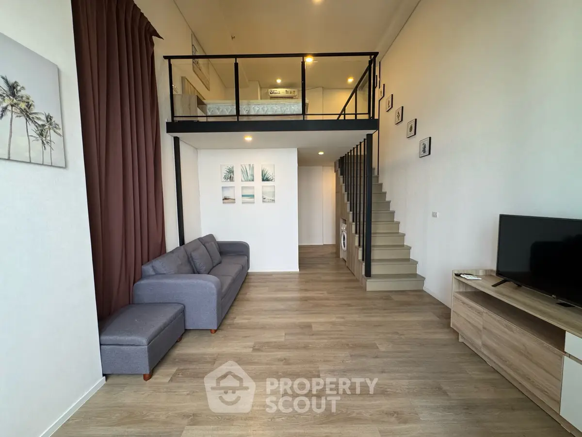 Modern loft apartment with mezzanine, stylish living area, and wooden flooring.
