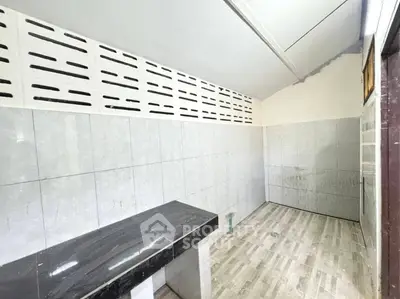 Spacious tiled room with countertop and high ceiling, ideal for versatile use.