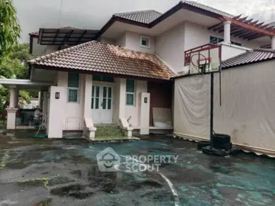 Charming two-story house with tiled roof and basketball hoop in spacious driveway.