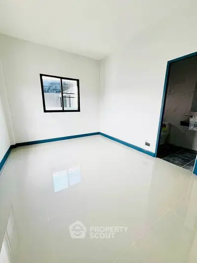 Spacious unfurnished room with glossy tiled floor and window, ideal for customization.