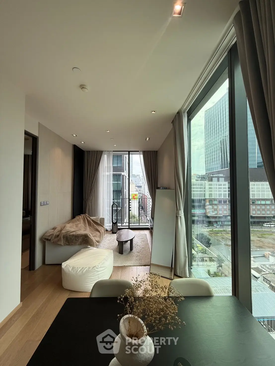 Modern living room with floor-to-ceiling windows and city view, featuring stylish decor and cozy seating area.