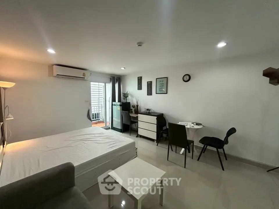 Modern studio apartment with sleek furnishings and natural light, featuring a cozy living area and compact dining space.