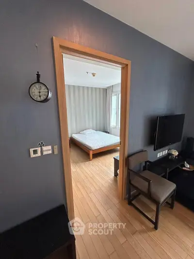 Cozy apartment interior with a view into a minimalist bedroom featuring wooden flooring and modern decor.