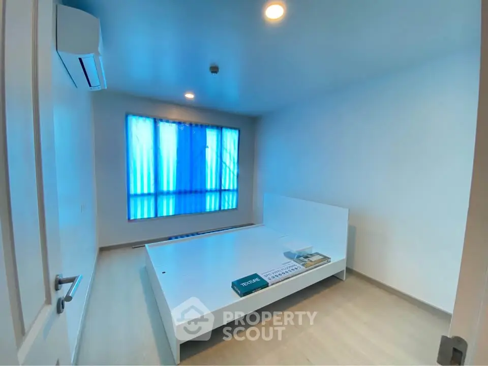 Spacious minimalist bedroom with modern air conditioning and large window.