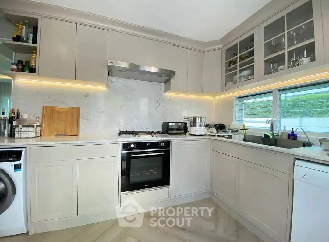 Modern kitchen with sleek cabinetry, built-in oven, and natural light from large window.