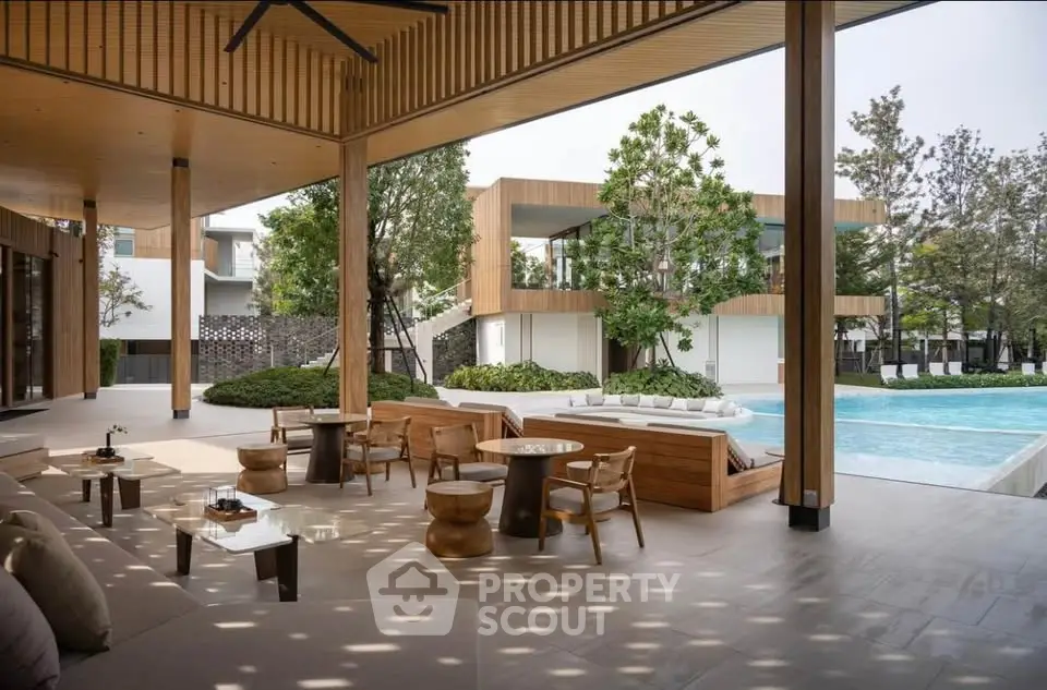 Luxurious outdoor pool area with modern seating and lush greenery, perfect for relaxation and entertainment.