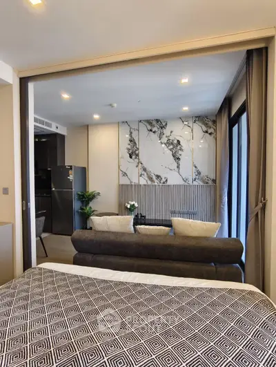 Modern open-plan living room with stylish decor and kitchen view, featuring marble accents and cozy seating.