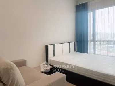 Modern bedroom with large window and cozy sofa, perfect for urban living.