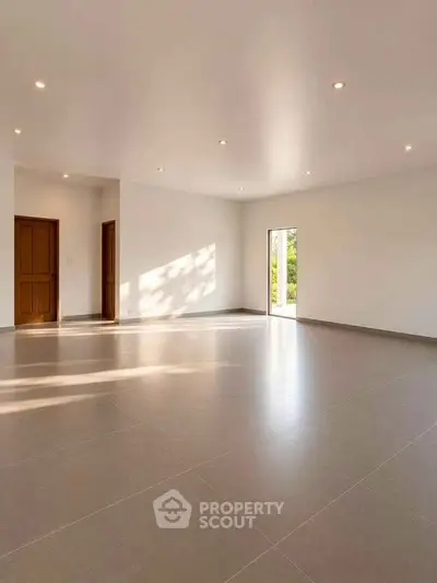 Spacious empty room with large windows and natural light, perfect for customization.