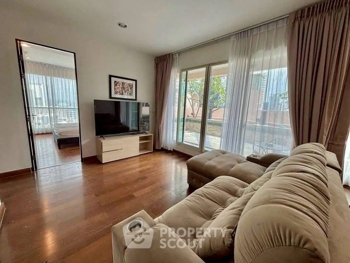 Spacious living room with plush sofa and large windows offering garden view