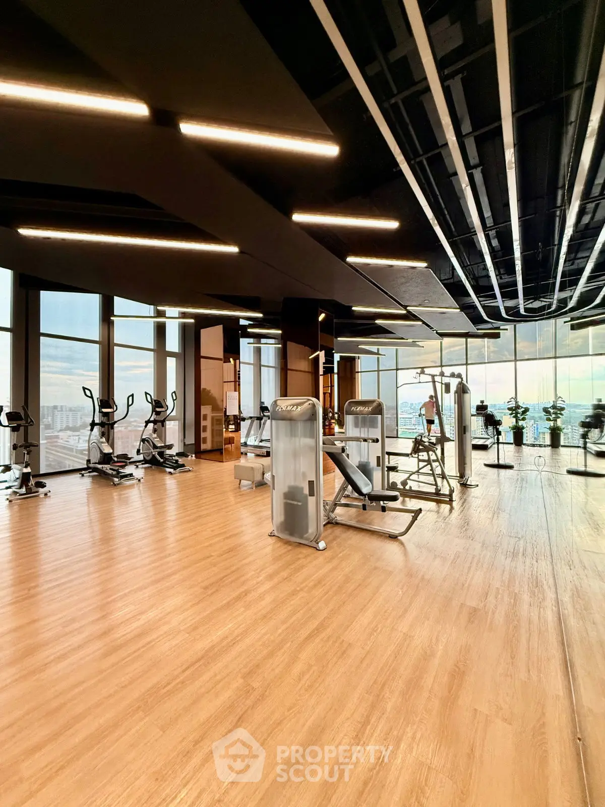 Spacious modern gym with panoramic city views and state-of-the-art fitness equipment.
