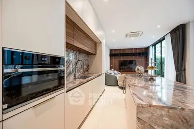 Luxurious modern kitchen with marble countertops and open layout, featuring sleek appliances and spacious design.