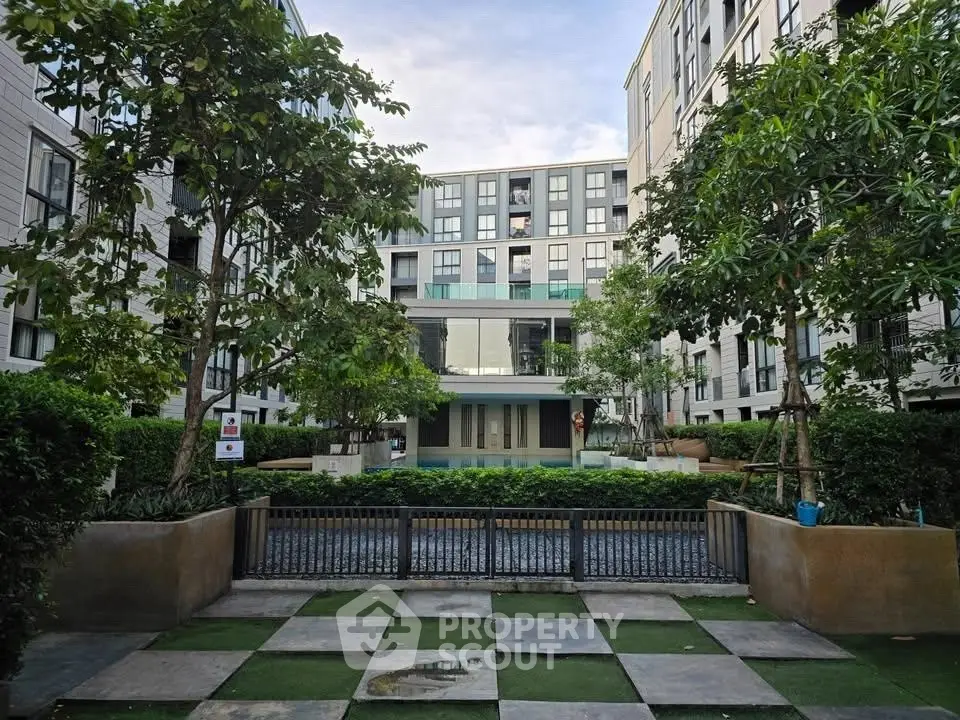 Modern apartment complex with lush greenery and contemporary architecture.