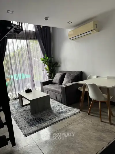 Modern living room with sleek furniture and large windows offering natural light.