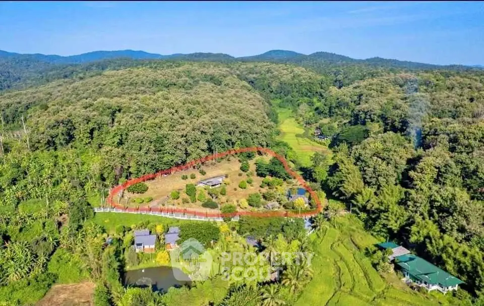 Scenic aerial view of lush green landscape with property surrounded by forested hills.