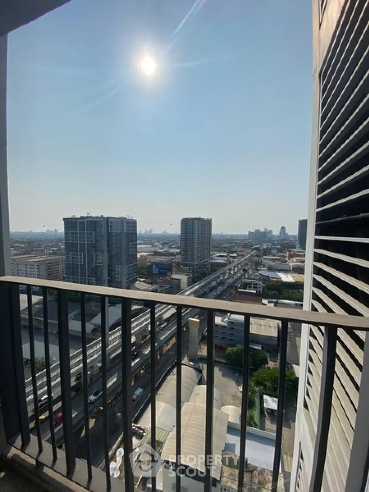 Stunning cityscape view from high-rise balcony with clear skies and urban skyline.