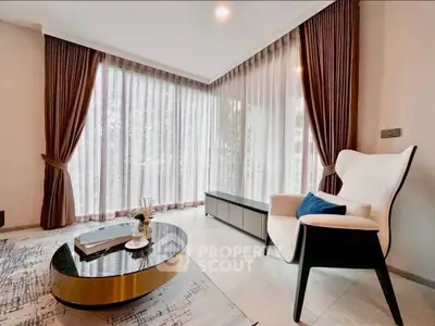 Elegant living room with large windows, stylish furniture, and natural light.
