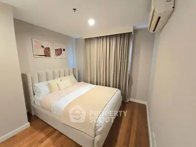 Cozy bedroom with elegant decor and natural light, featuring a plush bed and stylish artwork.