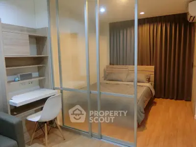 Modern studio apartment with glass partition separating bedroom and study area, featuring sleek design and cozy ambiance.
