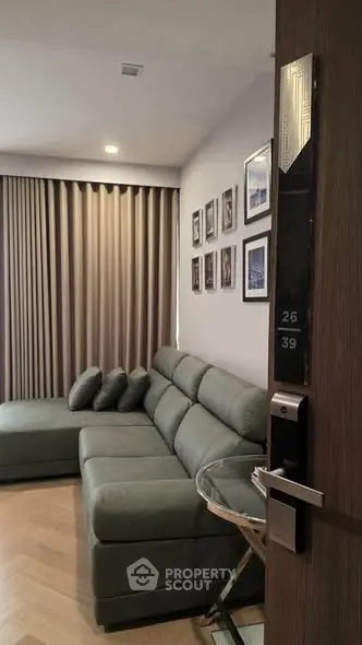 Modern living room with stylish gray sofa and wall art, featuring elegant wood flooring and soft lighting.
