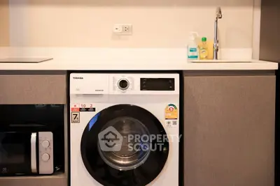 Modern kitchen with washing machine and sink, featuring sleek cabinetry and appliances.