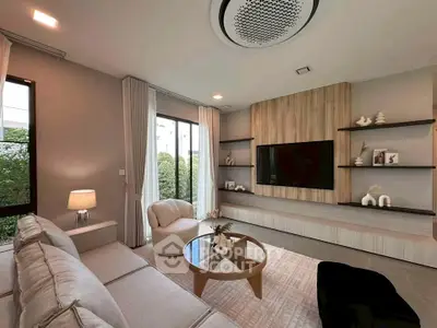 Modern living room with stylish decor and large TV, featuring cozy seating and elegant shelving.