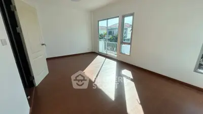 Bright and spacious bedroom with large windows and wooden flooring in modern home.