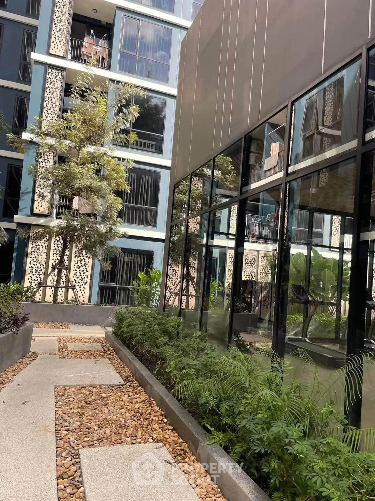 Modern apartment building exterior with lush greenery and stylish architecture.
