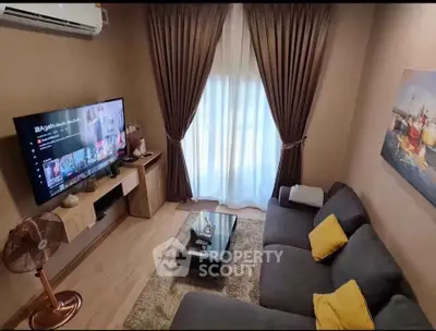 Cozy living room with modern decor, large TV, and elegant curtains.