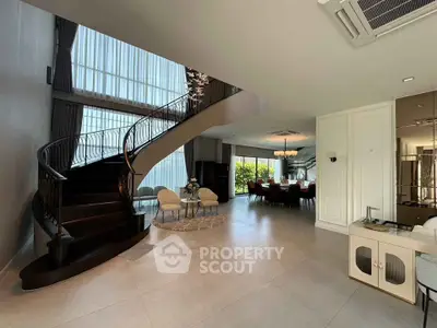 Luxurious open-plan living room with elegant staircase and dining area, featuring floor-to-ceiling windows.