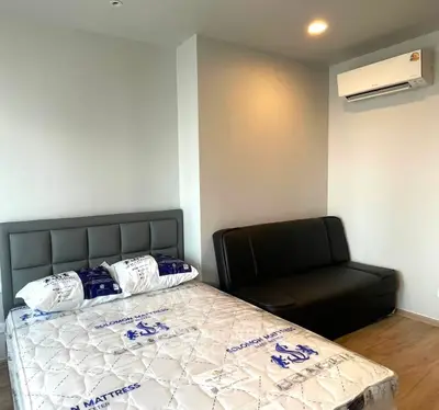 Modern bedroom with stylish bed and sofa, featuring sleek air conditioning unit.