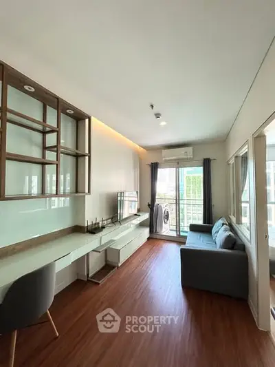 Modern living room with sleek furniture and balcony access, featuring wooden flooring and ample natural light.