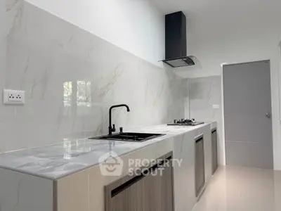 Modern kitchen with sleek marble countertops and gas stove in contemporary home.