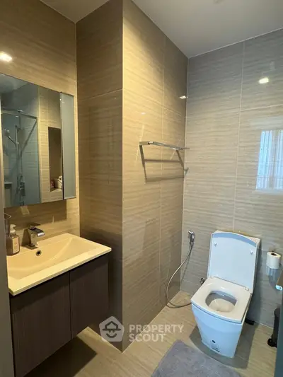 Modern bathroom with sleek fixtures and elegant tile design, featuring a spacious vanity and contemporary toilet.