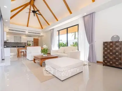Luxurious open-plan living room with high ceilings and modern decor, featuring elegant white furniture and natural light.
