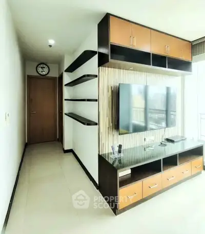 Modern living room with sleek TV unit and ample storage in a bright apartment