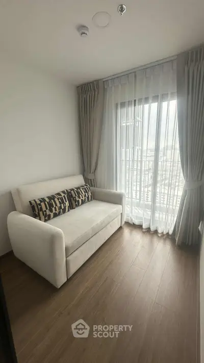 Cozy living room with a plush sofa and large window offering city views.