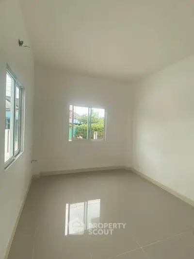 Spacious empty room with large windows and glossy tiled floor, perfect for customization.